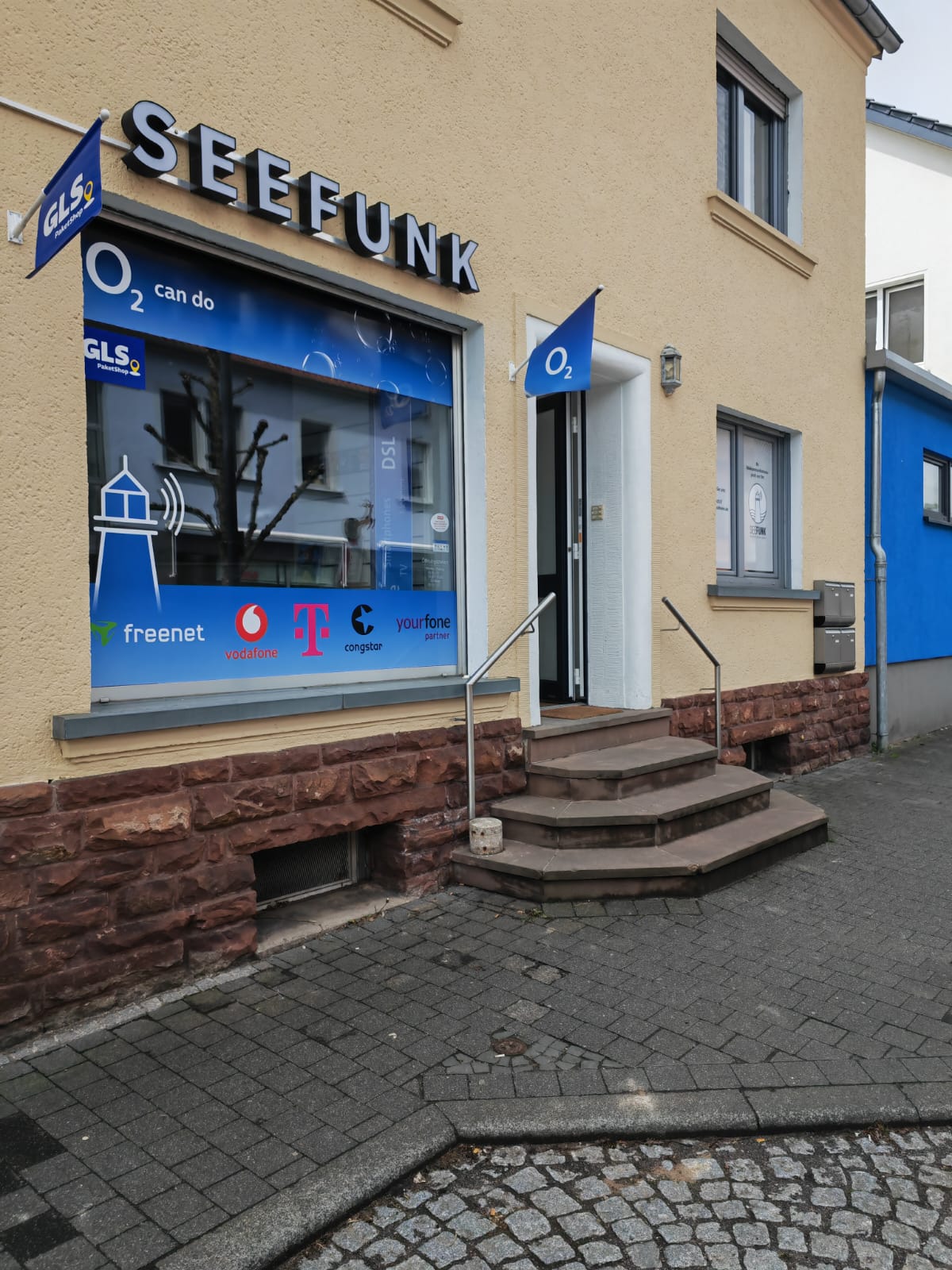 Eingang des SEEFUNK Shops mit o2-Fahne und GLS PaketShop-Schild
